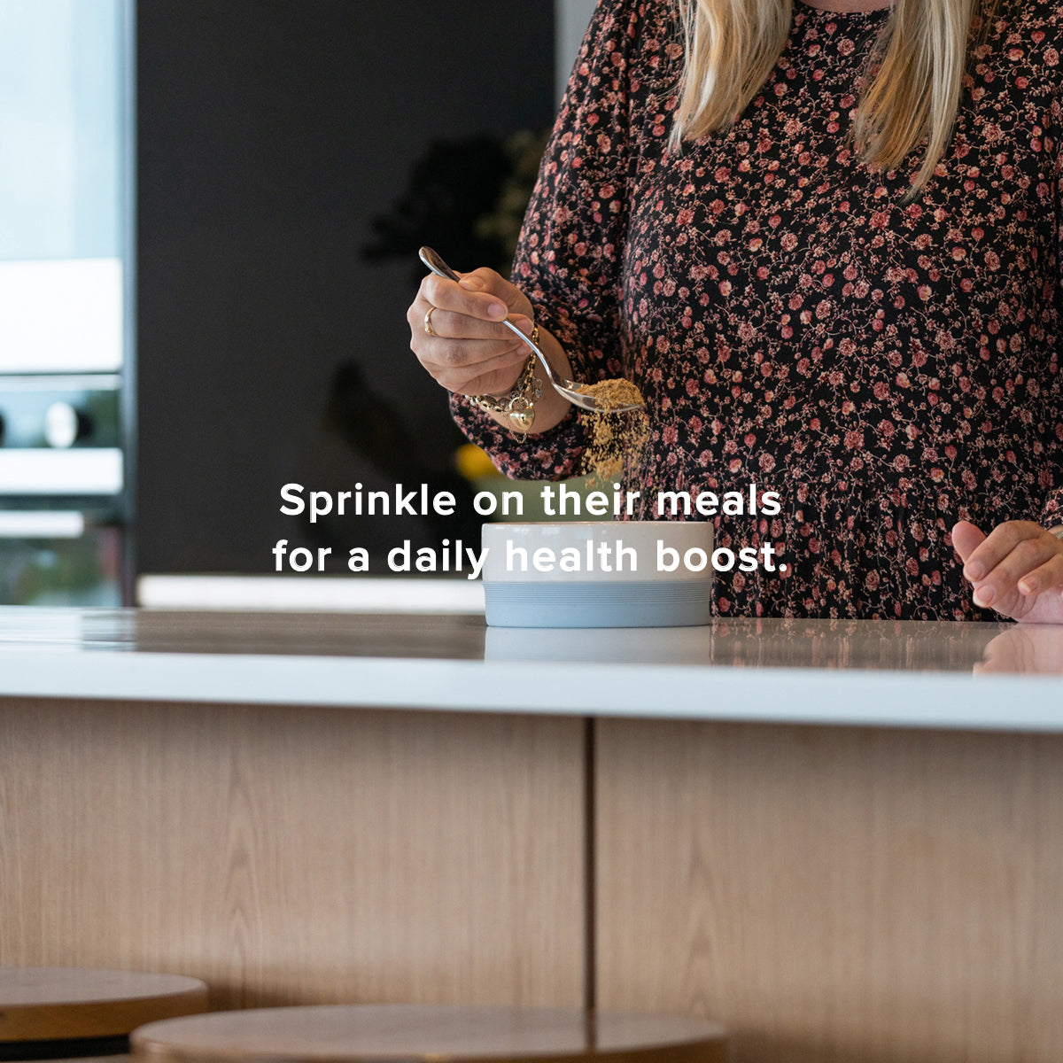 sprinkle on their meals for a daily health boost, woman putting powdered supplement into dog feeding bowl,  lifestyle image