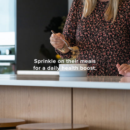 sprinkle on their meals for a daily health boost, woman putting powdered supplement into dog feeding bowl,  lifestyle image